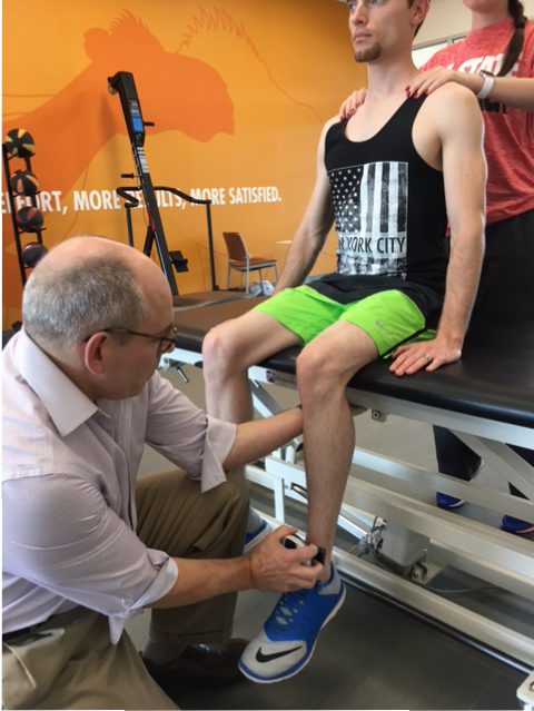 A man is undergoing muscle testing with the assistance of a microFET®2.