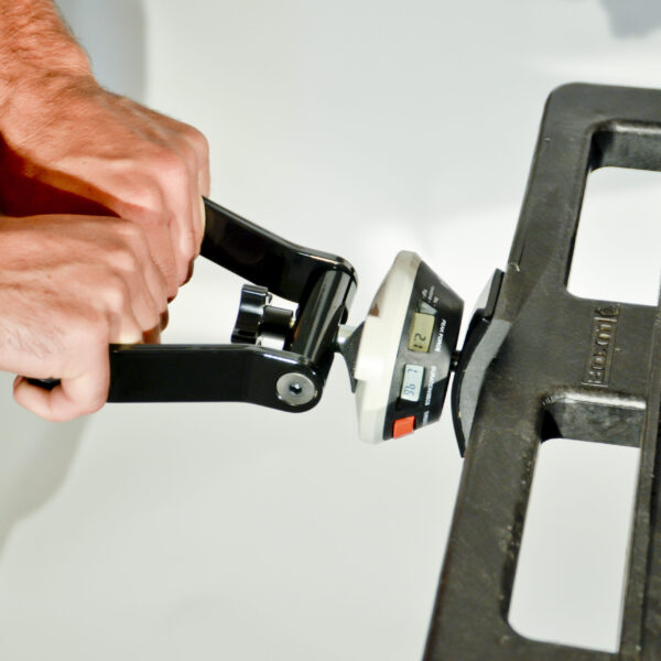 A man is using the ergoFET Digital Force Gauge to measure a piece of metal.
